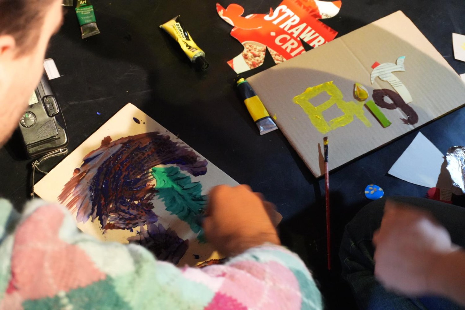 Participants paint onto cardboard salvaged from packaging.