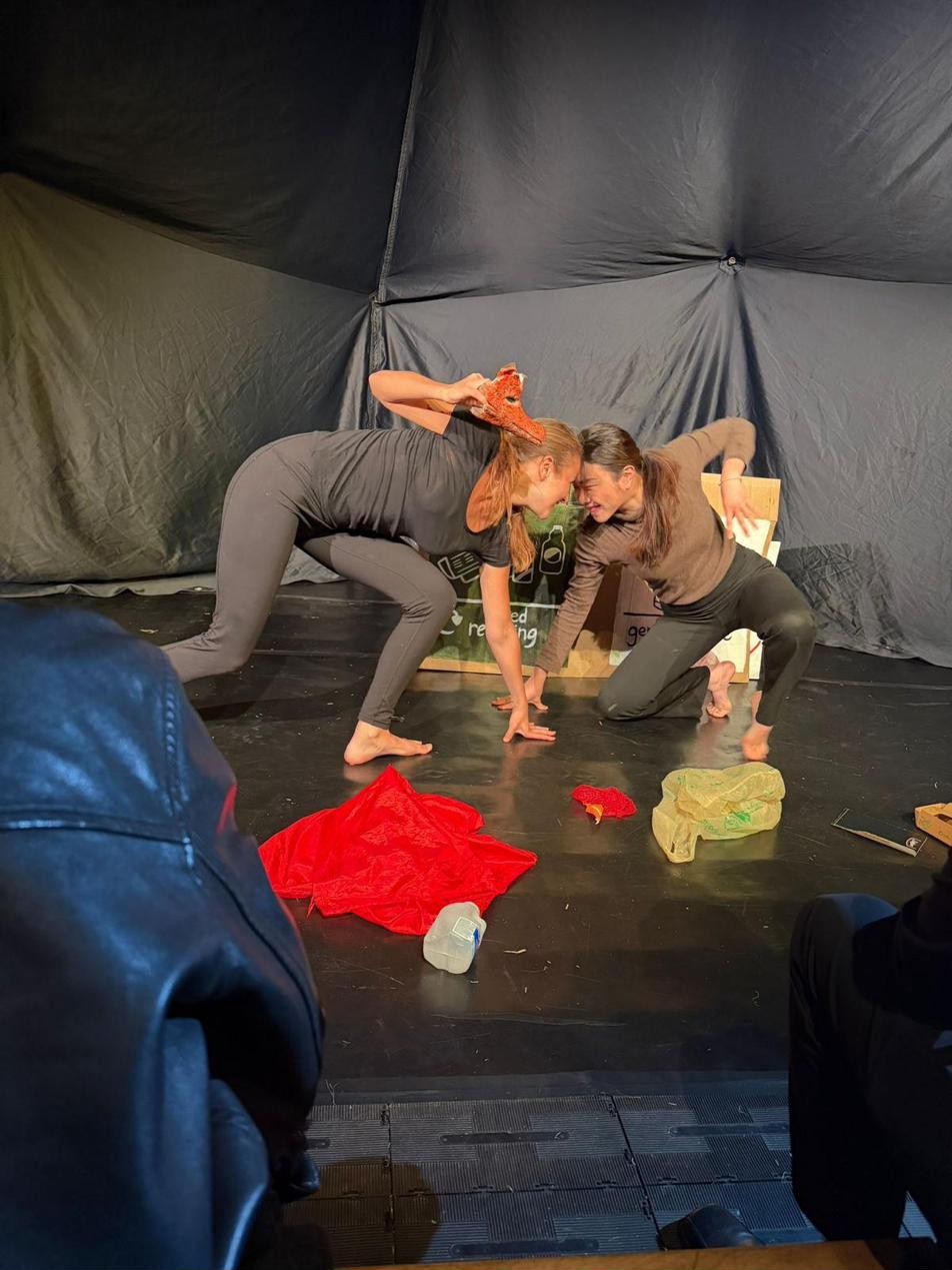 A physical duet between the two performers, bodies intertwined.