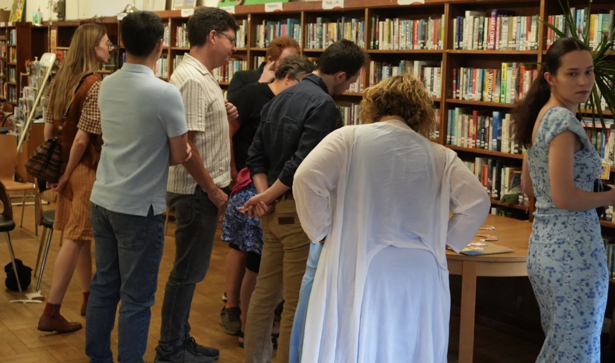 Participants stand around a library table looking at the art made in the workshop.