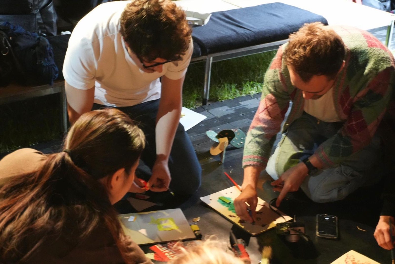 Three participants lean in over their artworks in progress.